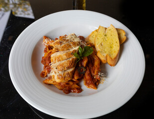 Grilled Chicken in a spicy chili and olive tomato sauce served with penne pasta, garlic bread and parmesan