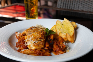 Grilled Chicken in a spicy chili and olive tomato sauce served with penne pasta, garlic bread and parmesan