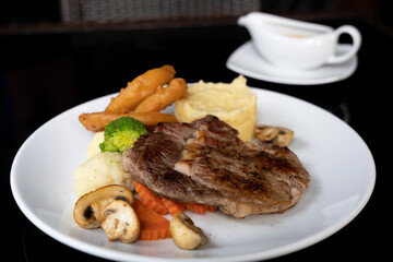 Rib eye beef steak with mashed potatoes mushrooms, onion rings. Served with pepper sauce