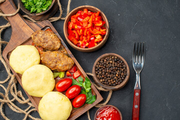 Top view of delicious cutlets chopped vegetables greens for dinner on dark background
