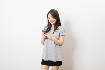 Fototapeta premium Beautiful Asian woman standing and smile using mobile smart phone looking to camera on a white background.