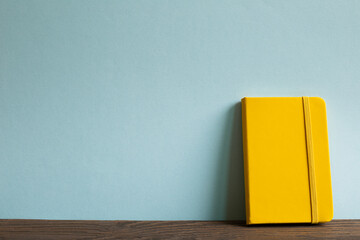 Yellow diary note book on wooden desk. sky blue background