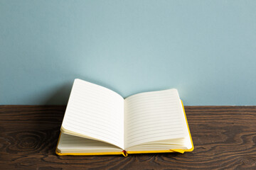 Open note book on wooden desk. sky blue background