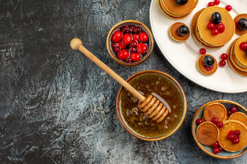 Half shot of classic pancakes on wooden cutting board honey in a white bowl on gray background