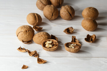 Few whole walnuts on white table with one broken