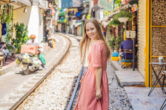 Woman is walking of Hanoi city railway. Perspective view running along narrow street with houses in Vietnam. Hanoi train street, old house and railroad. Vietnam reopens after coronavirus quarantine