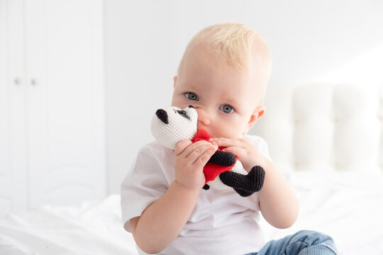 blonde baby boy playing with crocheted toy on bed.
