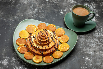 Half shot of pancake decoration on a green plate and a cup of coffee on gray background