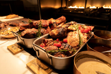 BBQ station at a buffet with prime rib, lamb rack and sauces