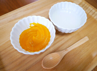 木のトレーの上に置かれたかぼちゃとお粥の離乳食