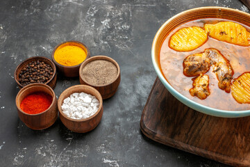 Side view of mixed spices chicken soup on wooden chopper board