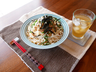 テーブルに置かれた、夏にぴったりの冷たいおろし納豆うどんと麦茶