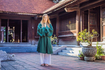 Naklejka premium Woman tourist in national vietnamese dress in Temple of Literature in Hanoi in Southeast Asia, Vietnam. Vietnam reopens after coronavirus quarantine COVID 19