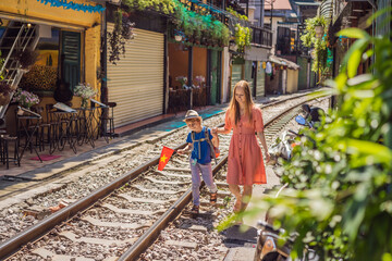 Mother and son travelers walk around railway paths which go through residential area in Hanoi city. Hanoi Train Street is a famous tourist destination. Vietnam reopens after coronavirus quarantine