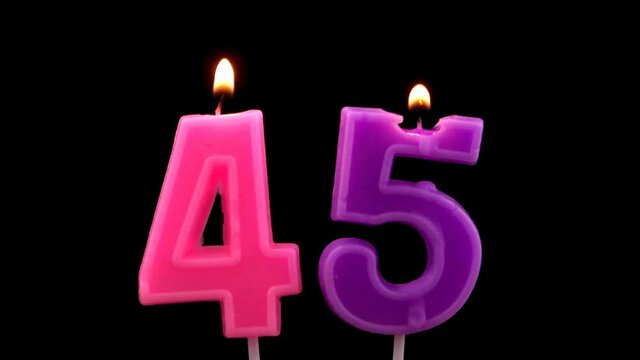 Burning birthday candles isolated on black background, number 45