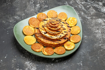 Top view of pancake decoration on a green plate for breakfast on gray background
