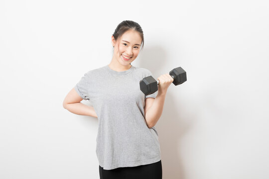 Beautiful young Asian woman lifting dumbbells smiling and energetic isolated over white background. Healthy lifestyle.