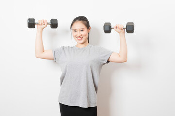 Beautiful young Asian woman lifting dumbbells smiling and energetic isolated over white background. Healthy lifestyle.