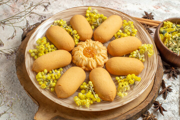 sideward view of a plate of cookies and some type of dry herbs around it on marble background