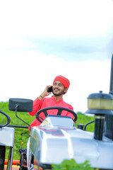 Naklejka premium Young Indian farmer talking on smartphone at field