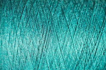 Background of a close up of aquamarine thread for sewing fabric: seamless pattern of twisted thread in a trendy color, soft focus, selective focus, space for text
