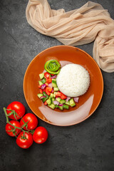 Above view of vegan dinner with rice and different types of vegetables on dark table