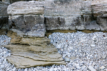mountain textures of stones with interlayers of gypsum, colored quartz, clay, sand and other layers of various ores, with different textures, color and density, in gypsum ore quarry.
