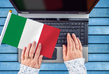 woman hands and flag of Italy on computer, laptop keyboard 
