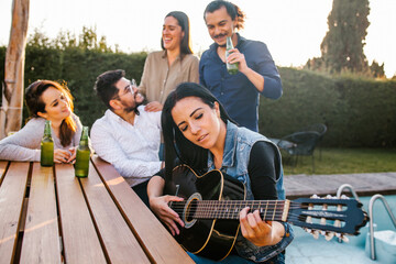 Mexican friends drinking beer on the terrace and latin woman playin a guitar in Mexico city