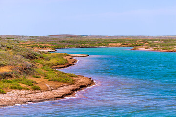 A lake with pink water near the shores and blue in the middle