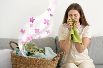 Young woman smelling clean laundry at home