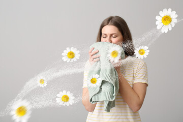 Young woman smelling clean laundry on grey background