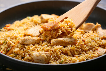 Bowl with tasty pilaf and wooden shovel