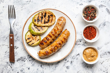 Plate with delicious grilled sausages, vegetables and spices on table