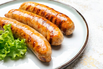 Plate with delicious grilled sausages on table, closeup