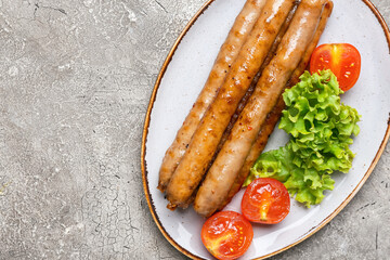 Plate with delicious grilled sausages and vegetables on table