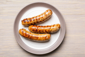 Plate with delicious grilled sausages and vegetables on table