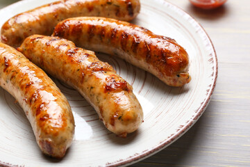 Plate with delicious grilled sausages and vegetables on table, closeup