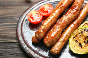 Plate with delicious grilled sausages and vegetables on wooden table, closeup