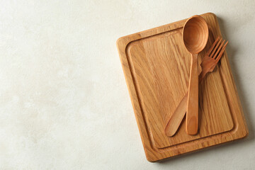 Wooden board and cutlery on white background