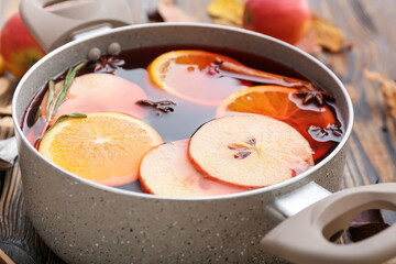 Saucepan with hot mulled wine on table, closeup