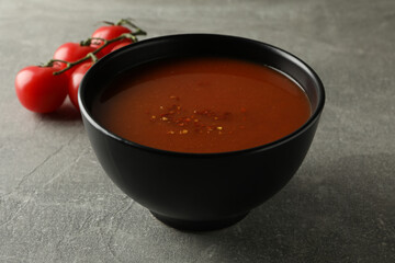 Bowl of tasty tomato soup on gray background