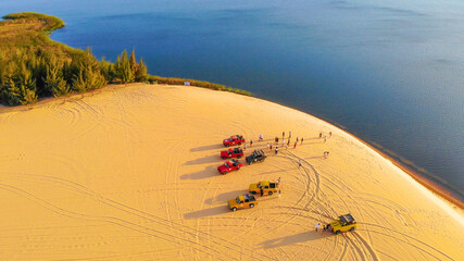 Fototapeta na wymiar Aerial view of Bau Trang lake (raw of automobiles with blue sky in desert, beautiful landscape of white sand dunes), the popular tourist attraction place in Mui Ne, Vietnam.
