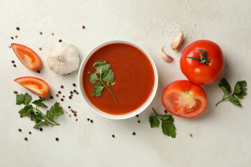 Fototapeta na wymiar Bowl with tomato soup and ingredients on light background