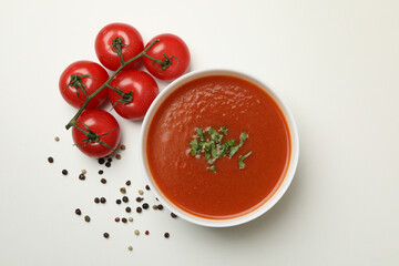 Bowl with tomato soup and ingredients on white background