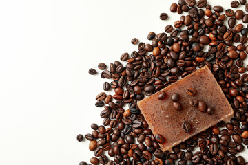 Piece of natural soap and coffee seeds on white background