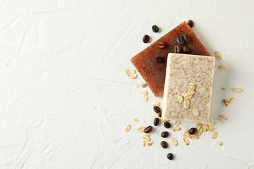 Natural soap, oat and coffee seeds on white table