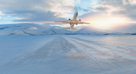 Passenger airplane fly up over take-off runway snowy mountains in the background - Snow-covered...