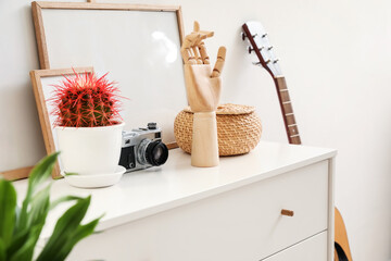 Wooden hand with stylish decor on chest of drawers in interior of room