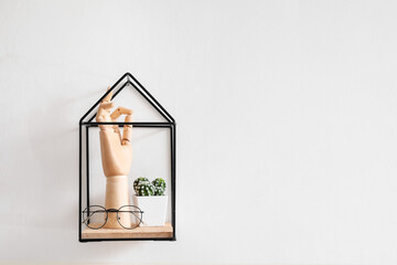 Wooden hand with eyeglasses and cactus on shelf